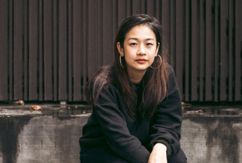 Aly Koh is a young Singaporean woman, sitting on a grey sofa.
