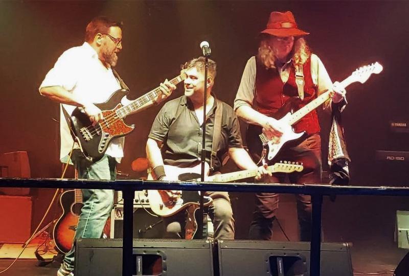 three men playing guitars on stage