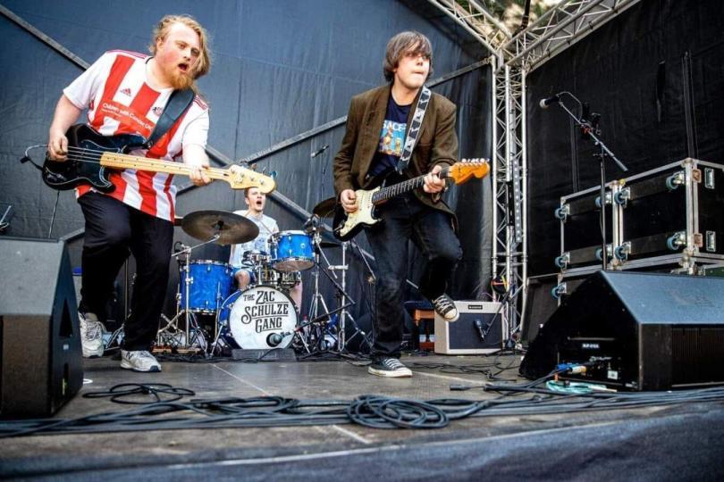three man blues band The Zac Schulze Gang performing on stage. Bass, guitar and drums.