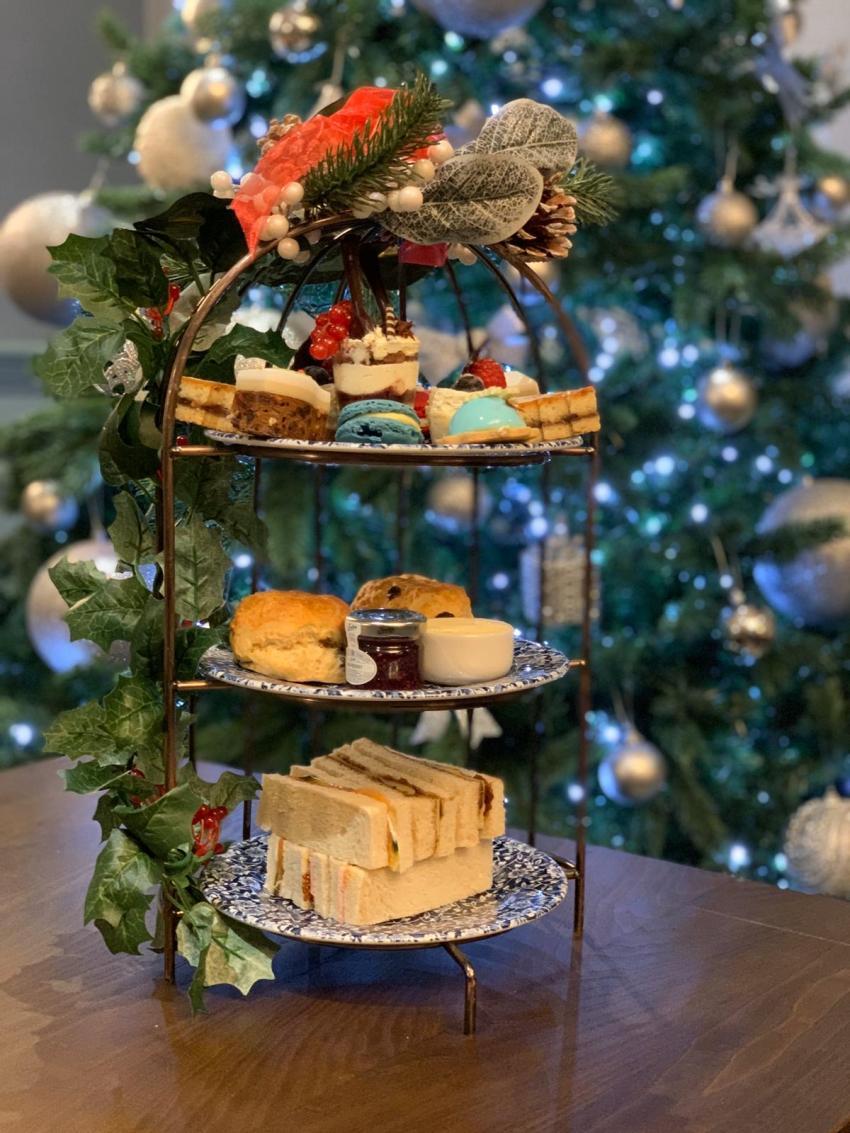 The image shows the adult's festive afternoon tea with a Christmas tree in the background.