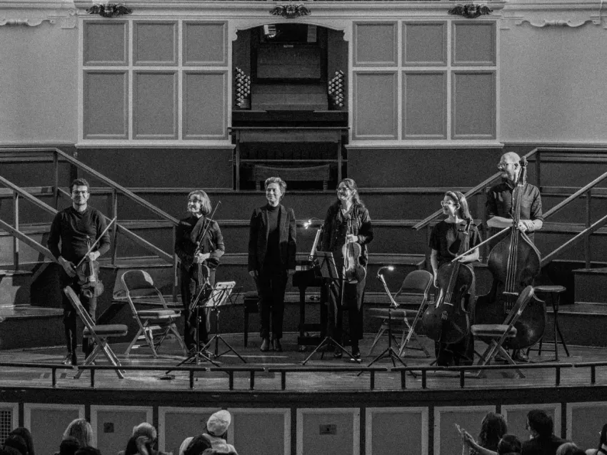 half a dozen classical musicians on stage holding their instruments