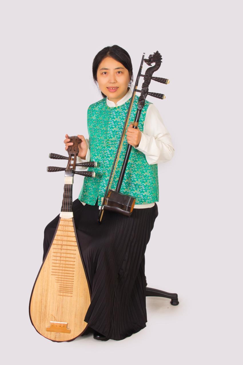 Chinese musician sitting on a chair holding a Chinese stringed instrument