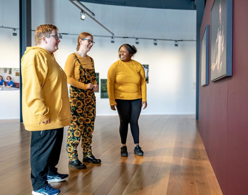 Three people in yellow in an art gallery