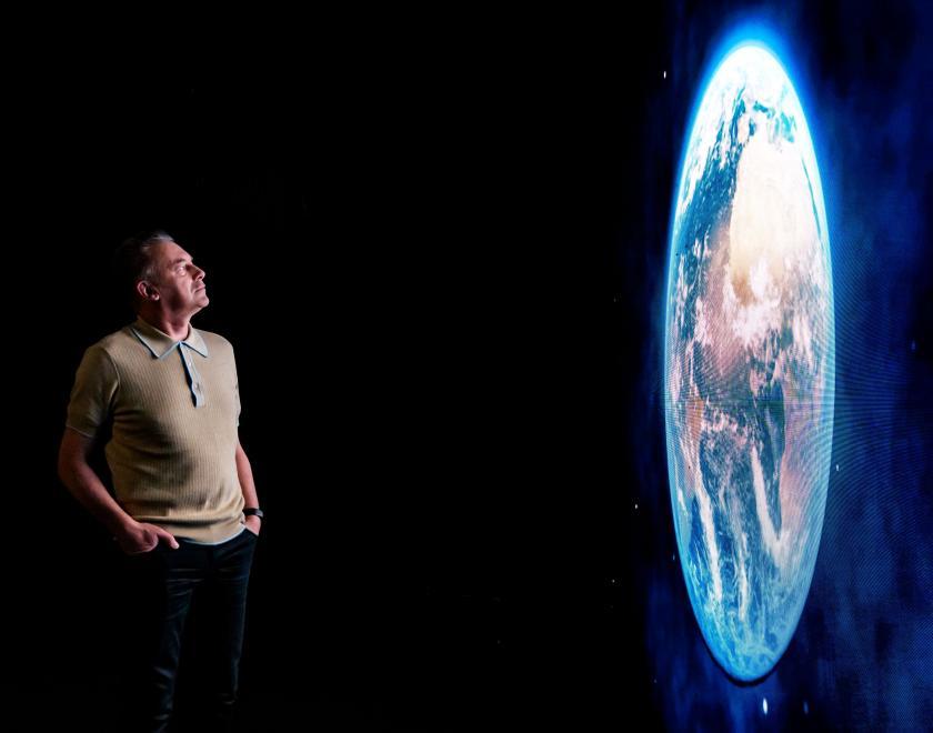 Chris Packham looks at a large image of planet Earth