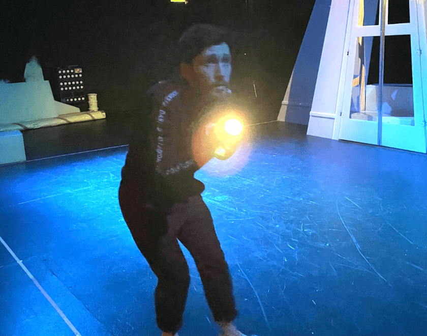 The Dark rehearsal image 1 - a performer holds up a battery powered torch