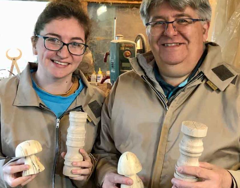 A smiling father and daughter holding woodturned toadstools.