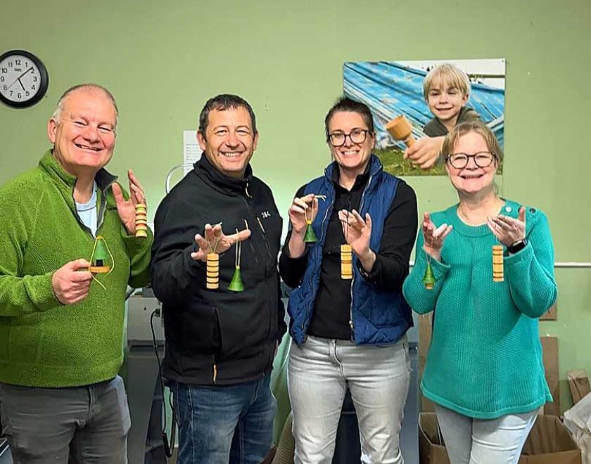 A group of men and women holding up their wooden tree ornaments