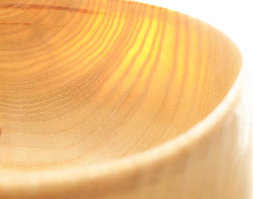 Close up view of a pale wooden bowl so thin the light is shining through it's side. making the grain visible.