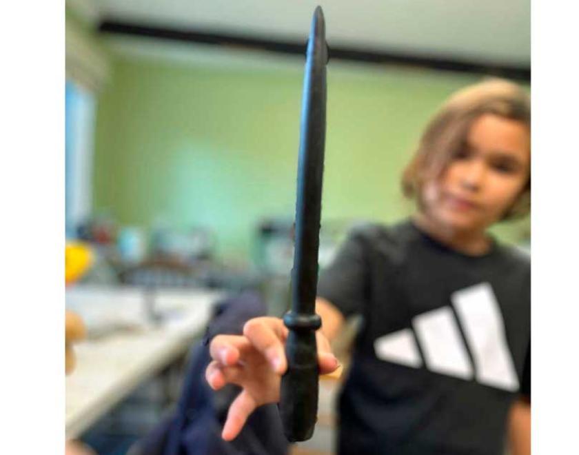 A girl holding a black wooden wand.