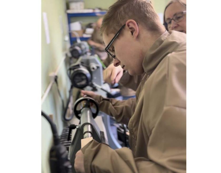 A woman learning to turn at a lathe.