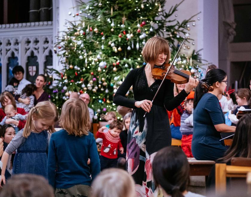 Violinist performing for children at a Christmas concert