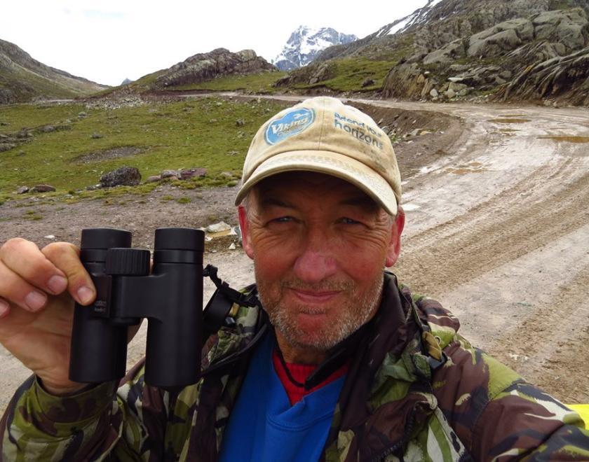 Photo of Gary Prescott in a baseball cap, holding up his binoculars