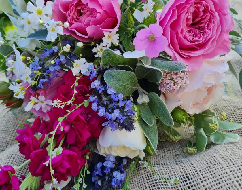 Bouquet of pink, lilac, white and maroon flowers lying flat on a hessian sack