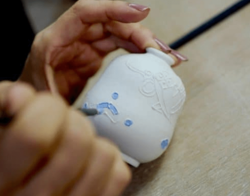 Hand colouring a ceramic pot