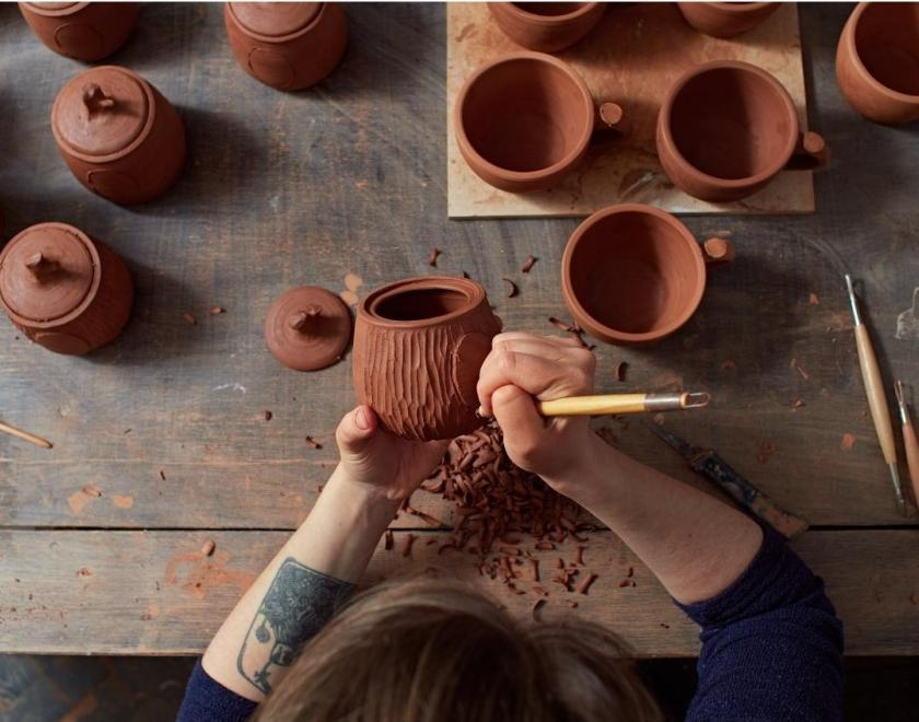 Person sat at the table working on a ceramic pot