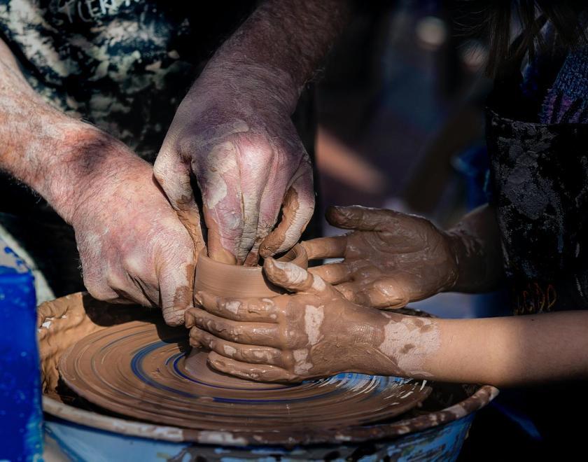 Hands working together at the pottery wheel