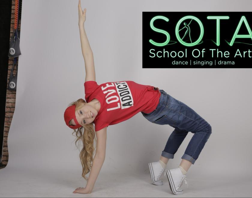 Photo of blonde dancer in a back bend wearing trainers, red t-shirt and baseball cap.