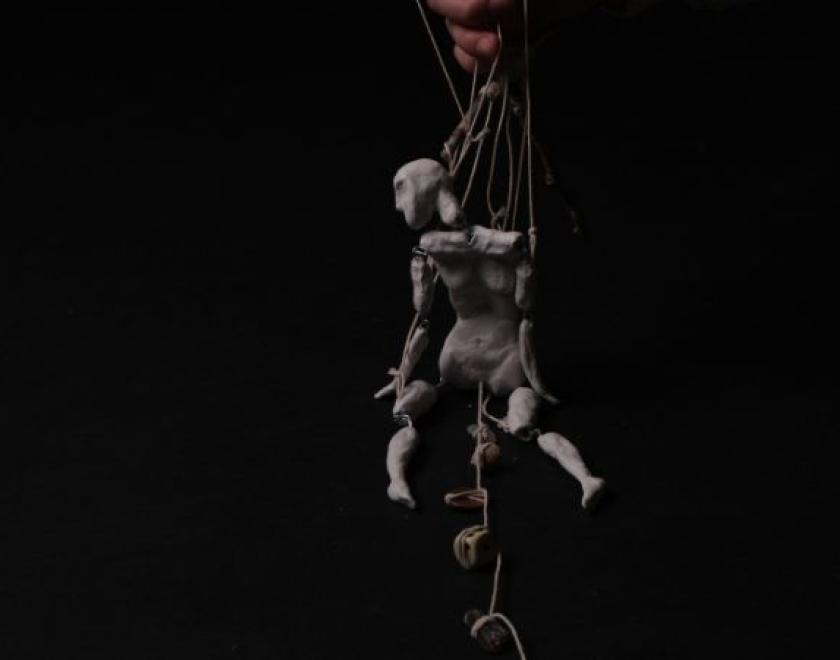 a puppet hanging on a black background