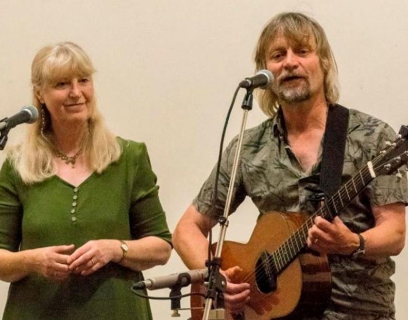 Jeff & Elaine Gillett performing together. Elaine is singing and Jeff is playing guitar.