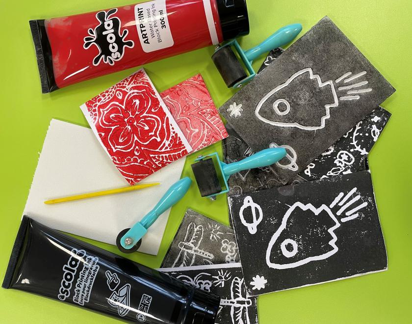 Image of assorted red and black paints, ink pads, sponges and examples of scratched art work. 