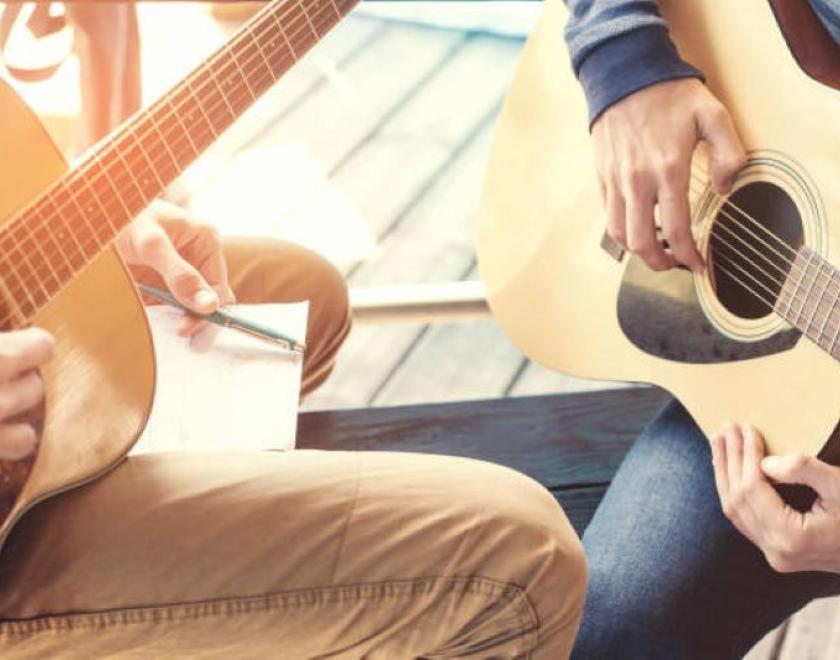 student and teacher holding guitars