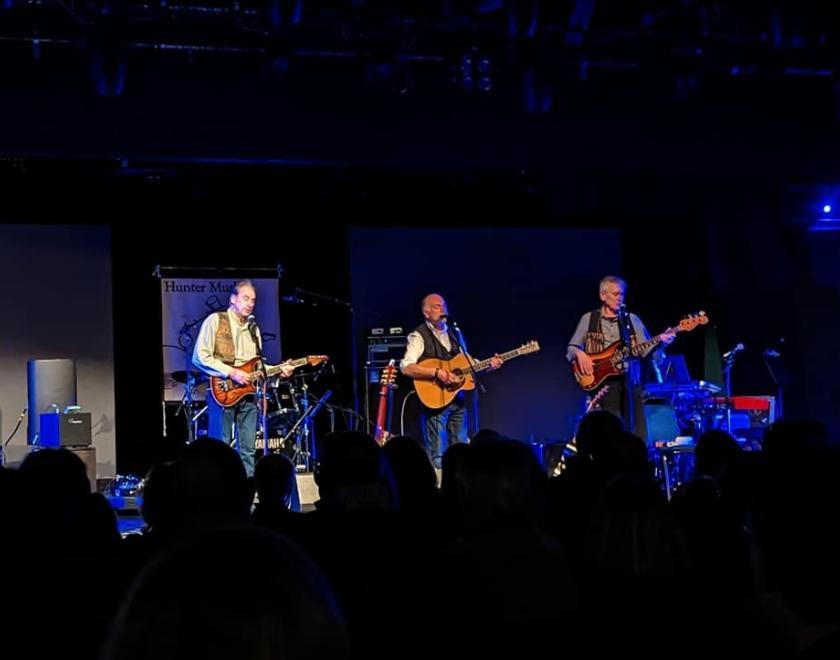 Photo of the trio Hunter Muskett on stage singing and playing guitars