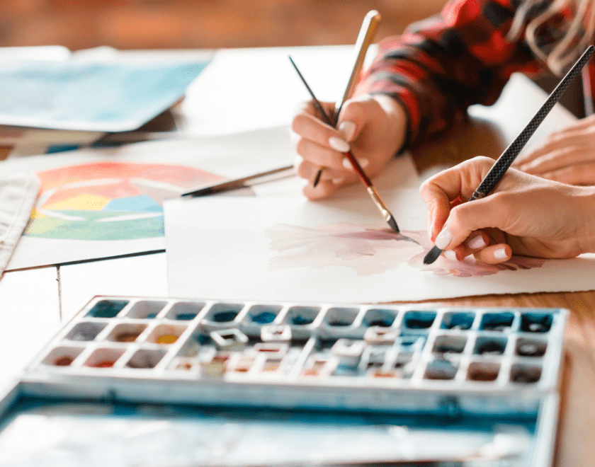 Hands drawing on paper with watercolours