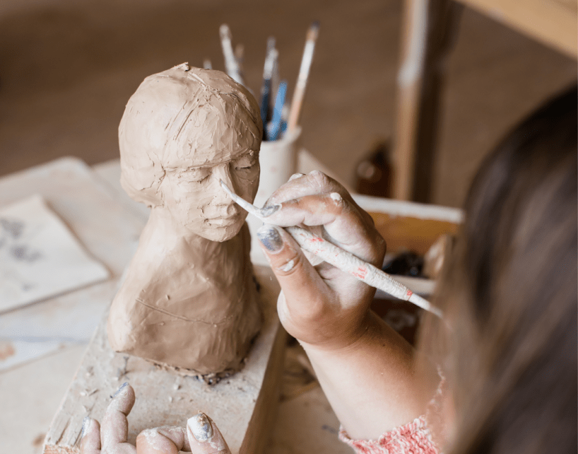 Hands sculpting a clay statue