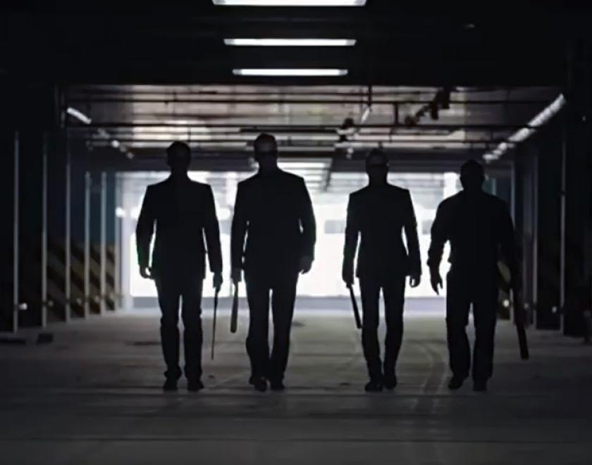 silhouette of four mafioso types walking into an underground garage