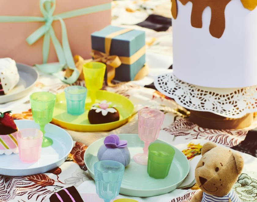 A picnic blanket propped with food and toys including an IKEA bear