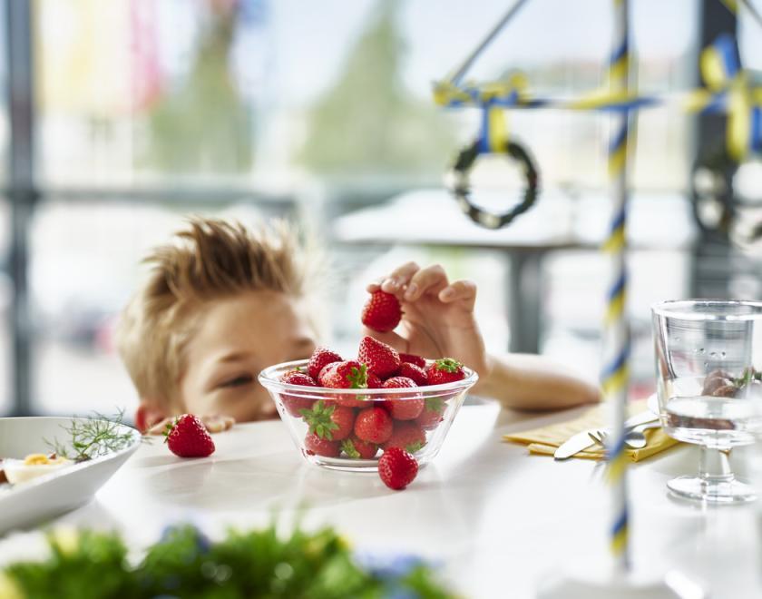 A swedish midsummer dinner table set with strawberries and a maypole decoration