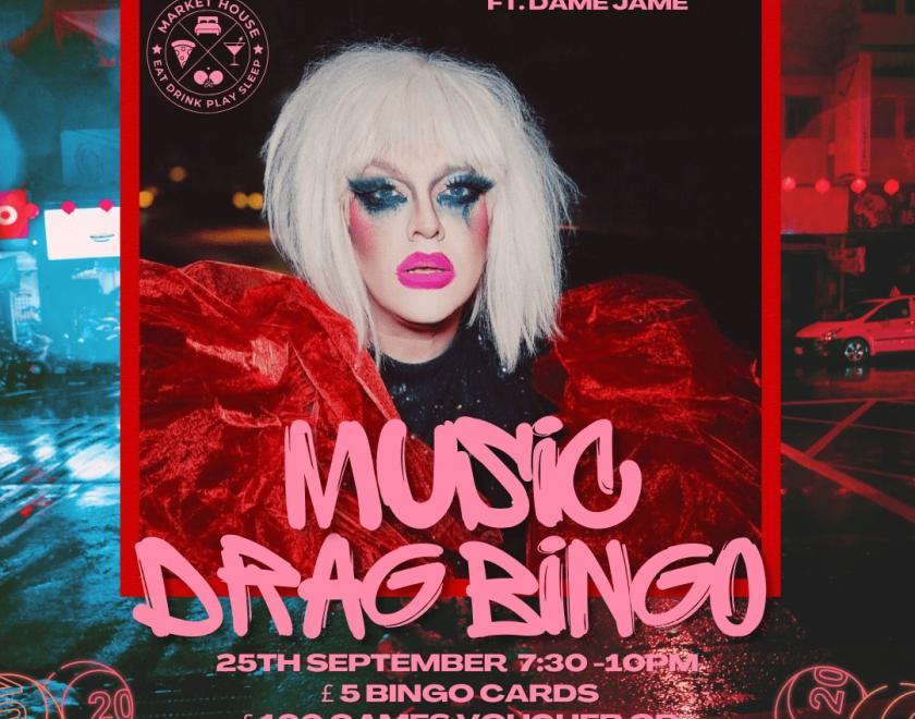 Image of Dame Jame with a white wig and pink writing, Music drag bingo