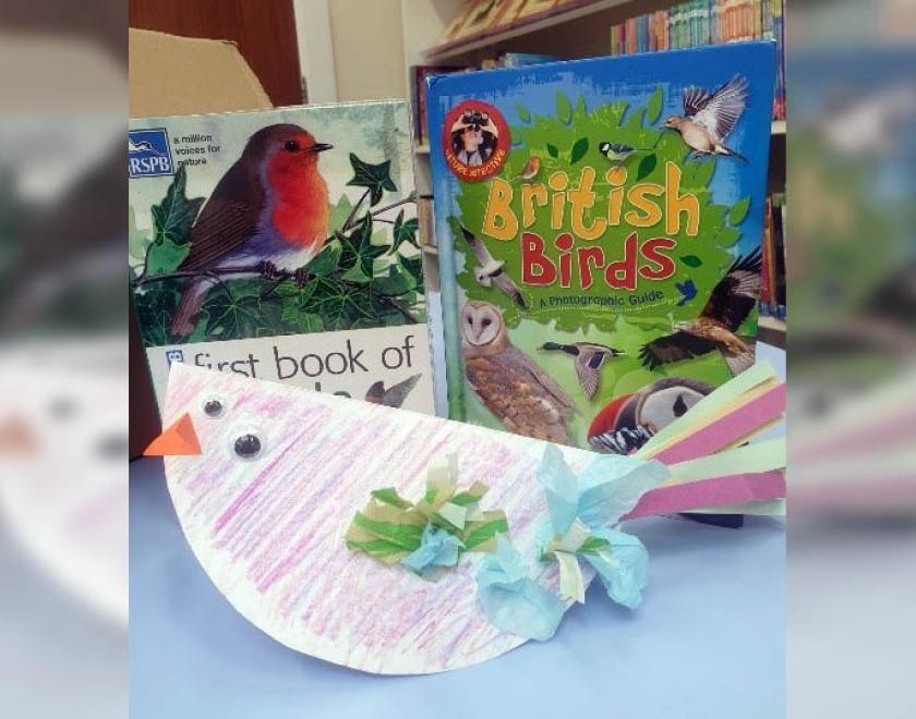 Photograph of a bird made from a paper plate in front of two bird books