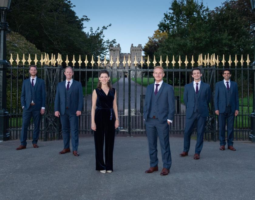 Queen's Six members standing in front of wrought iron gates