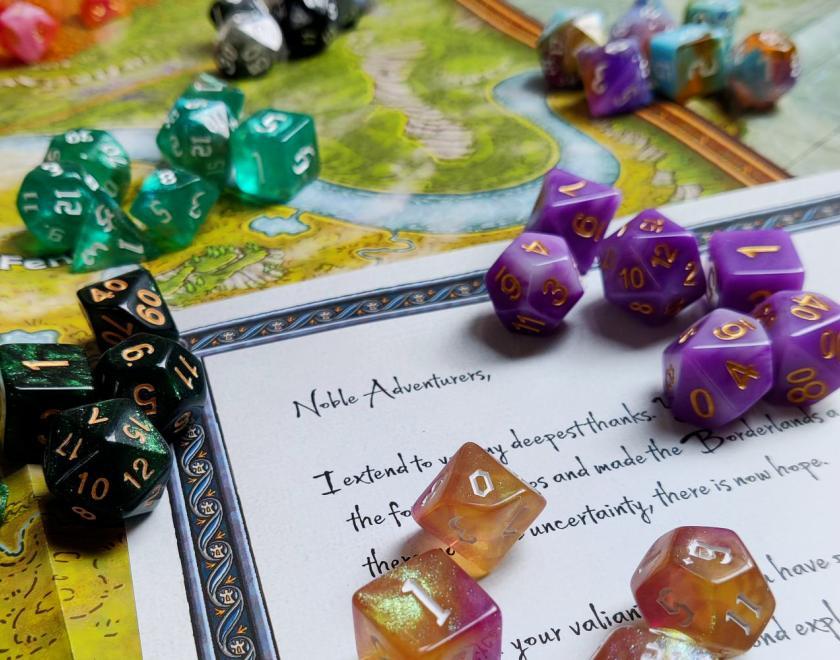 Colourful dice are laid out against a map and a letter