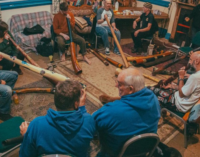 People sat in a circle playing didgeridoos