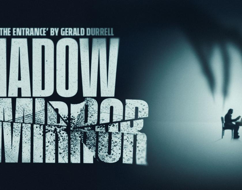 A large shadowy hand looms over a man seated at a desk