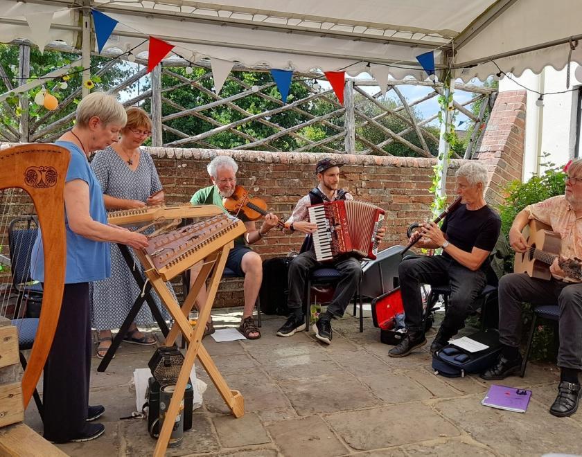 Photo of the Twagger Band playing at a folk club. They are singing and playing a variety of traditional instruments.