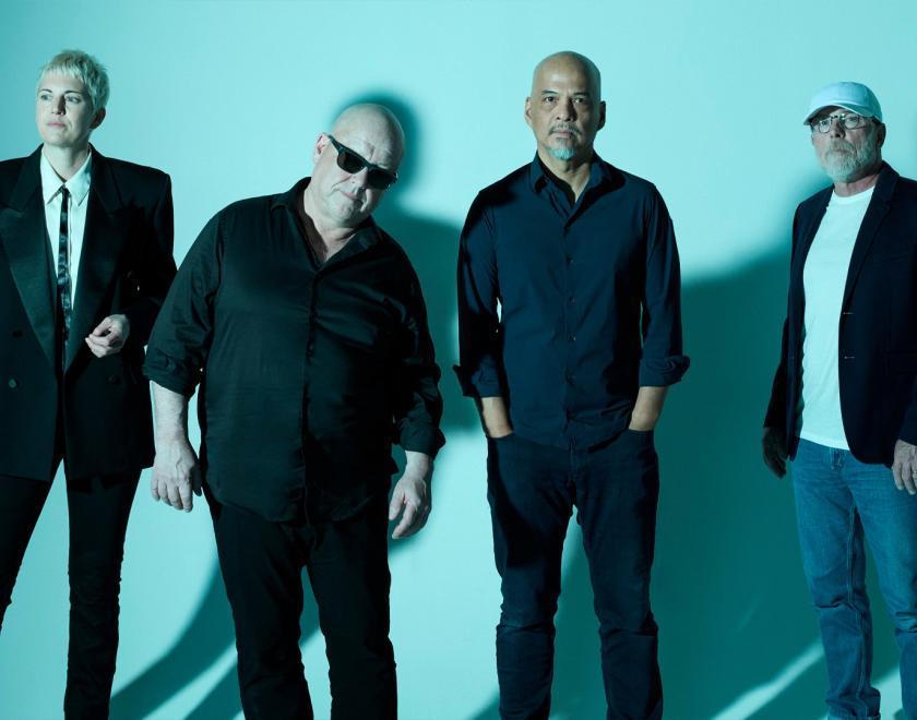 Members of he band Pixies against a bright turquois background