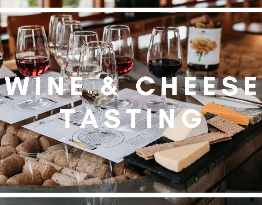 White text: Wine & Cheese Tasting, behind it is a table of wine glasses and cheese board 