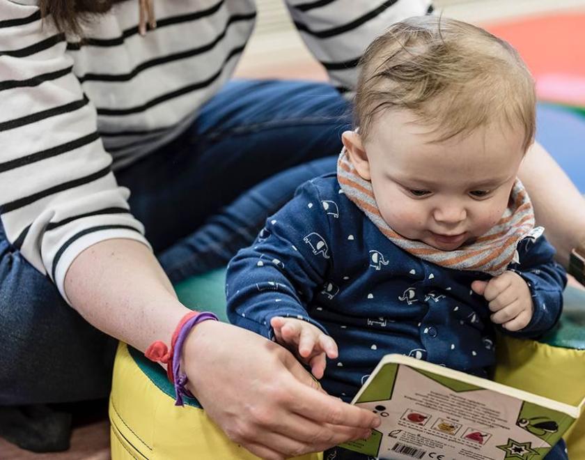 Adult reading a book to a baby