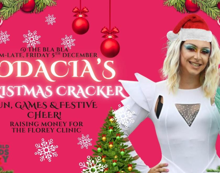 drag queen in a white outfit and Christmas hat on a pink background