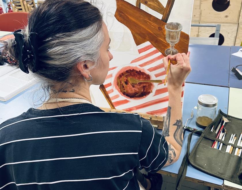 woman painting on an easel - seen of a dinner plate