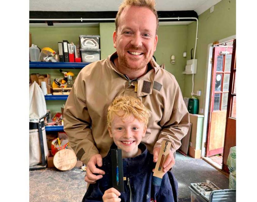 Father and son smiling and holding their handmade pens.