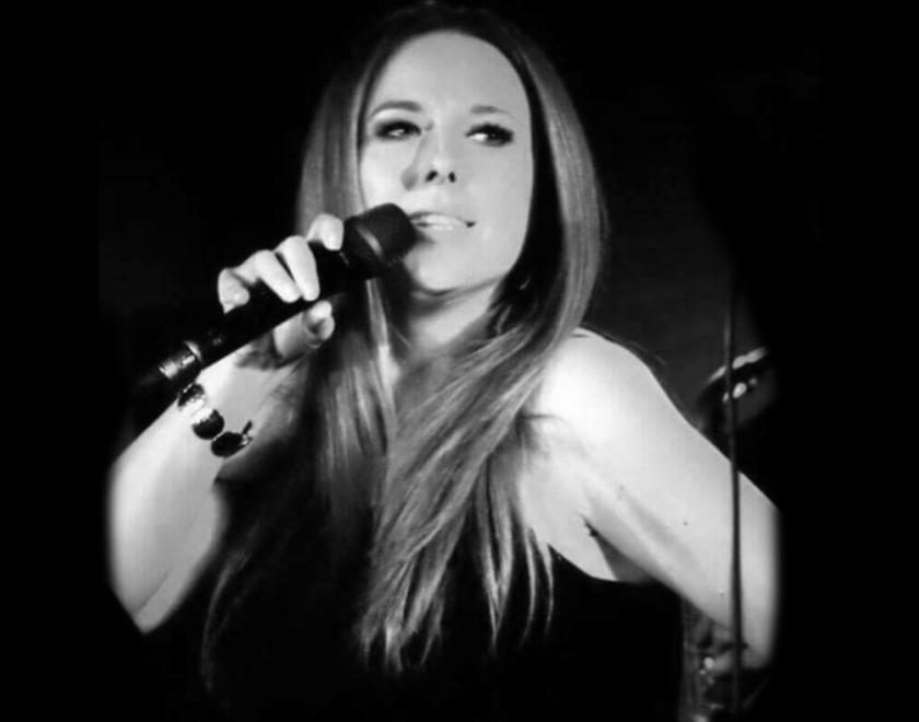 Black and white photo of singer Debby Bracknell. She has long hair and is singing into a microphone