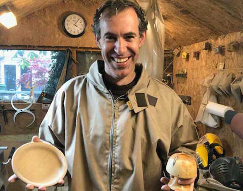 Man holding a wooden mushroom and bowl.