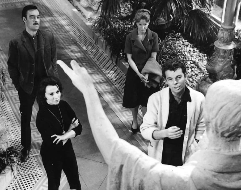 Four people standing in a garden looking up at a statue