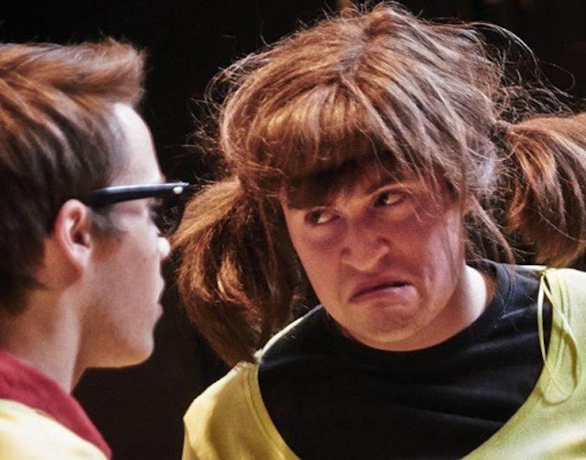 two improv comedy players. One has glasses, the other an ill-fitting wig.