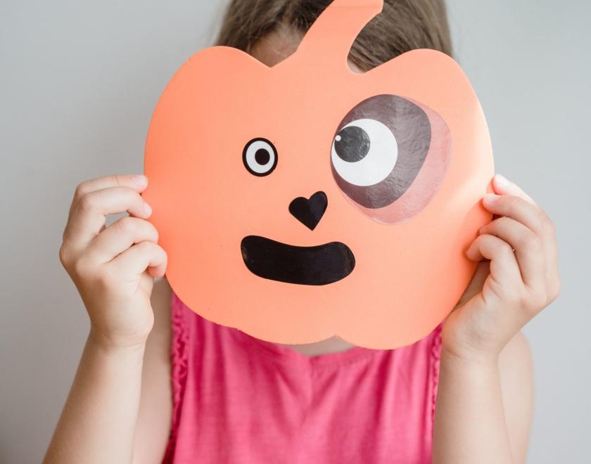 a young person with a pumpkin mask over their face