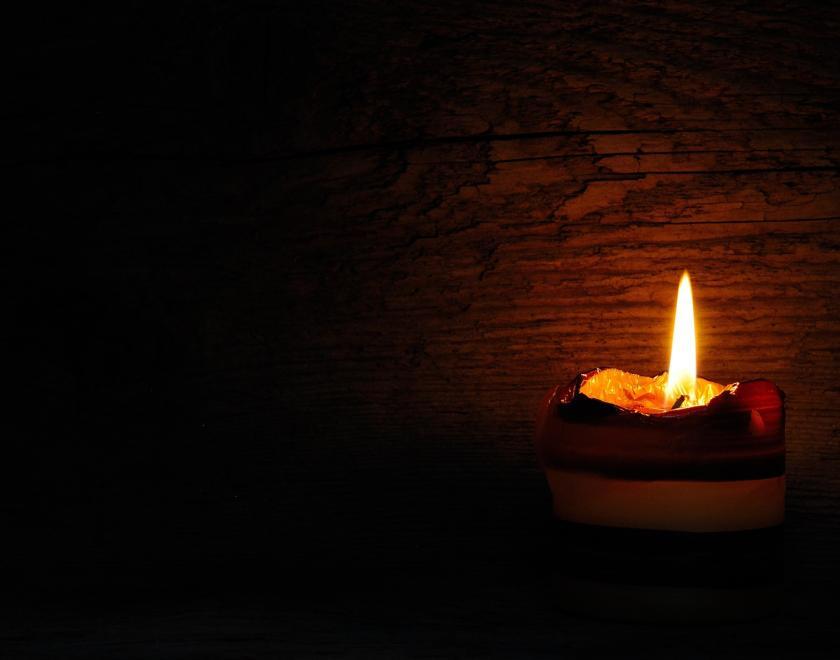 Photo of a candle burning with a wooden background.